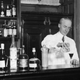 American barman Harry Craddock expertly mixes a drink in the American bar of the Savoy Hotel in London. Author of ‘The Savoy Cocktail Book’, Craddock invented such cocktails as the ‘Dry Martini’ and ‘White Lady’. (Photo by Topical Press Agency/Getty Images)